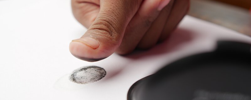 Man putting his fingerprint on a piece of paper.