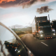 Semi trucking seen through car side mirror.